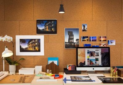Close-up of a creative workstation with a cork wall and desk lamp.