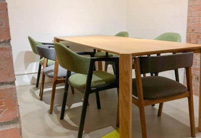 Meeting area with a large wooden table, green upholstered chairs, and a brick feature wall.