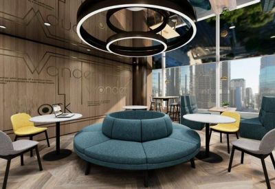 Communal breakout area with a central teal circular sofa, colorful chairs, and designer halo lighting.