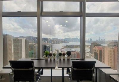 Two-person window-facing desk setup with black office chairs and panoramic harbor and city views.