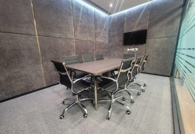 Modern meeting room with a dark wood table, ergonomic chairs, and grey fabric acoustic wall panels.
