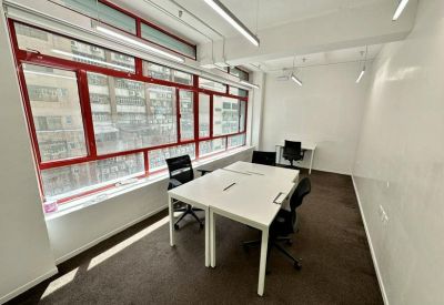 Bright private office suite featuring a large window with red frames and a four-person desk.