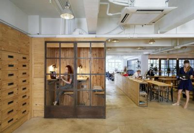 Open-plan workspace with private glass-fronted work booths and communal tables.