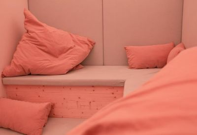 Cozy breakout nook with pink walls and numerous plush coral-colored pillows.