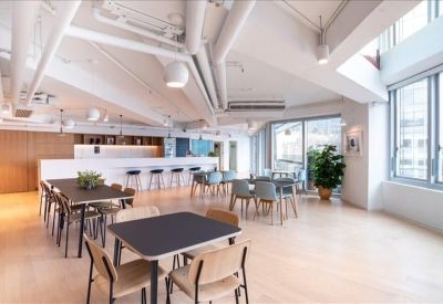 Spacious communal breakout area with various seating arrangements and exposed ceiling pipes.