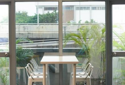 Tall white bar stools at a slender table overlooking a large window.