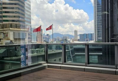 Outdoor balcony area with glass railings and views of surrounding city skyscrapers.