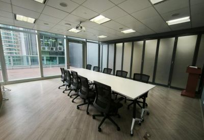 Spacious board room with a long white table, black chairs, and floor-to-ceiling windows.