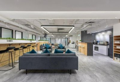 Shared workspace with sofa seating, breakfast bar, and a bright kitchen area in the background.