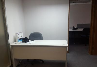 Private office suite featuring a white desk and an adjacent doorway leading to another workspace.