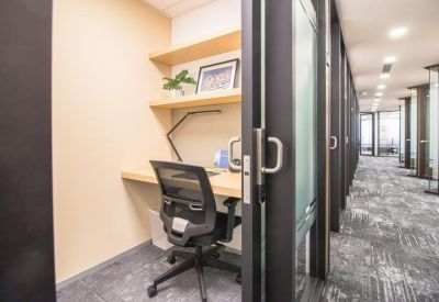Private glass-fronted workstation pod with a wooden desk and ergonomic chair.
