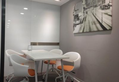Private meeting room with a white table, orange-accented chairs, and city-themed wall art.