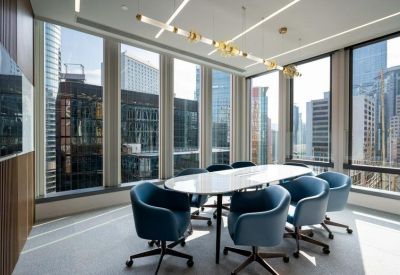 Sunlit meeting room with a white marble table and blue executive chairs.