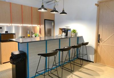 Modern communal kitchen and breakfast bar with wood cabinetry and stylish pendant lights.