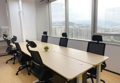 Bright office suite with a long shared desk and ergonomic seating near a window.