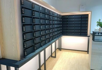 Mailroom featuring rows of black numbered mailboxes on a light wood wall.