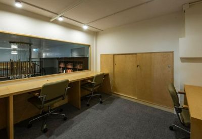Quiet study or focus area with wooden desks, office chairs, and a large window.