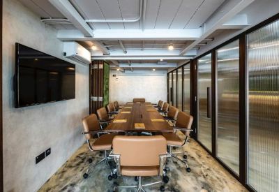 Modern conference room with a long wooden table, tan leather chairs, and glass walls.