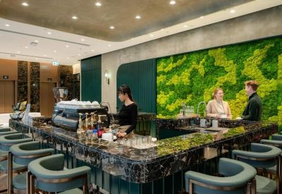 Modern espresso bar featuring a lush green moss feature wall and marble countertops.