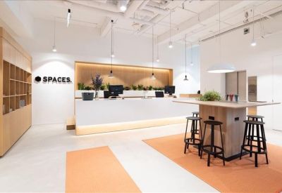 Bright reception area with white desk, branded signage, and a high-top wooden table.