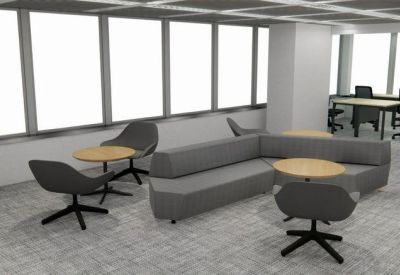Modern lounge area with a grey sectional sofa, round wooden tables, and large windows.