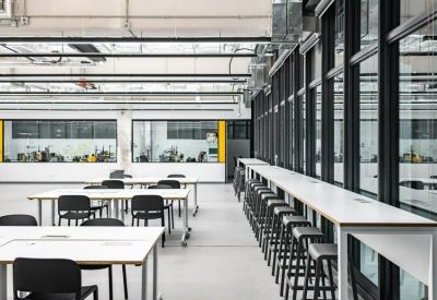 Open-plan workspace featuring white tables with black chairs and a long window-side breakfast bar.
