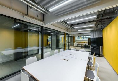 Professional meeting room with a large white table, grey chairs, and a bright yellow feature wall.