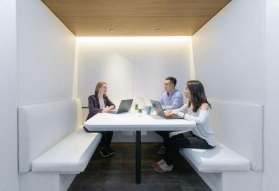 Modern meeting booth with integrated lighting, white benches, and a wooden ceiling.
