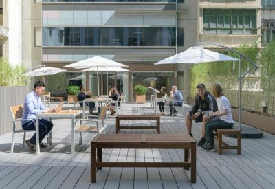 Outdoor terrace with wooden decking, seating, and large white umbrellas.