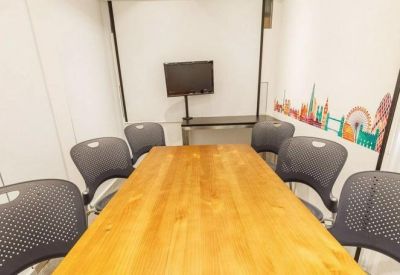 Meeting room with large wooden table and grey ergonomic chairs.