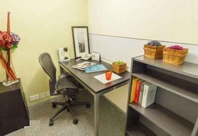 Private workspace with an ergonomic chair and a dark desk featuring decorative items.