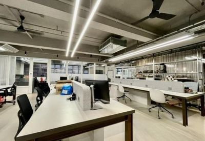 Long rows of white workstations with black task chairs in a bright, open-plan office space.