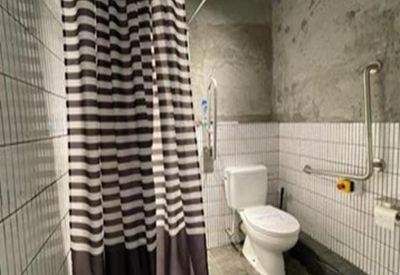 Modern bathroom with striped shower curtain, white tiling, and accessibility handrails.