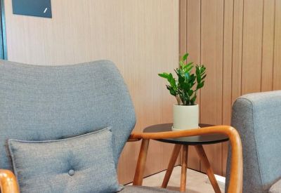 Modern grey armchair and side table with a small potted plant against a wood-paneled wall.