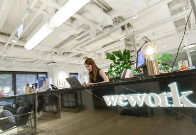 Reception desk with branded 'wework' sign and greenery.
