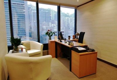 Private office featuring white armchairs and a wooden desk with a city view.