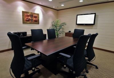 Corporate meeting room with dark wood table, black chairs, and wall art.