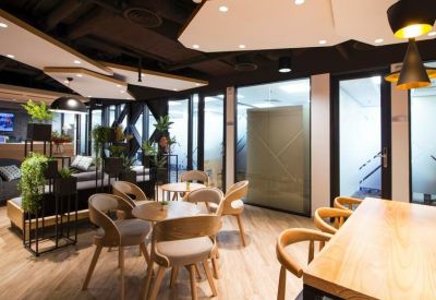 Chic breakout lounge with wooden round tables, designer chairs, and indoor plants.