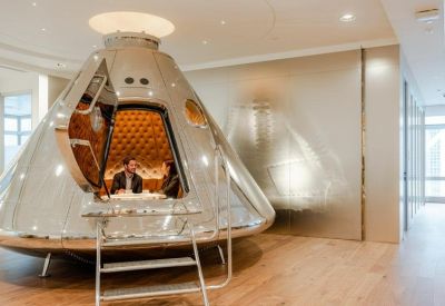 Unique metallic futuristic meeting pod shaped like a space capsule on wooden floors.