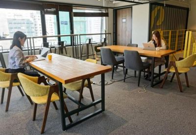 Bright coworking space with wooden tables, yellow chairs, and large windows.