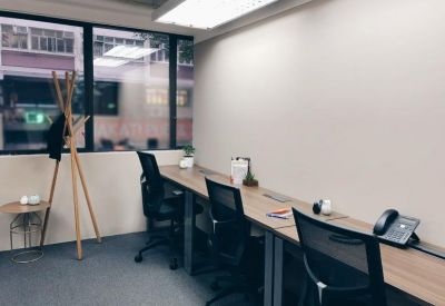 Private office with a long wooden desk, three ergonomic chairs, and large windows.