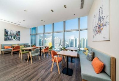 Spacious communal dining area with floor-to-ceiling windows and colourful orange and green chairs.