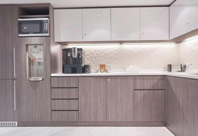 Modern office kitchen with wood-finish cabinetry and built-in appliances.