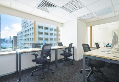 Bright open-plan workspace with white desks and large windows overlooking city buildings.