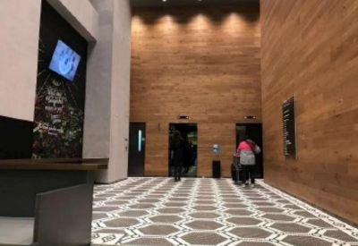Elevator lobby featuring wood-paneled walls and geometric floor tiling.
