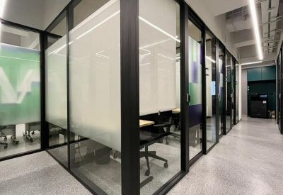 Corridor lined with glass-partitioned private office suites.