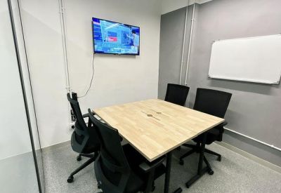 Small meeting room with a wooden table, black chairs, and a TV.