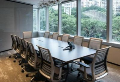 Professional boardroom with a large central table and floor-to-ceiling windows overlooking greenery.