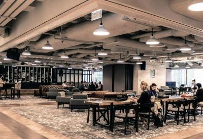 Large open-plan coworking space with various seating areas and industrial-style exposed ceilings.