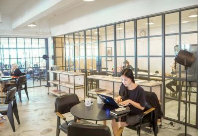 Open-plan coworking space with glass partition walls and modern seating.